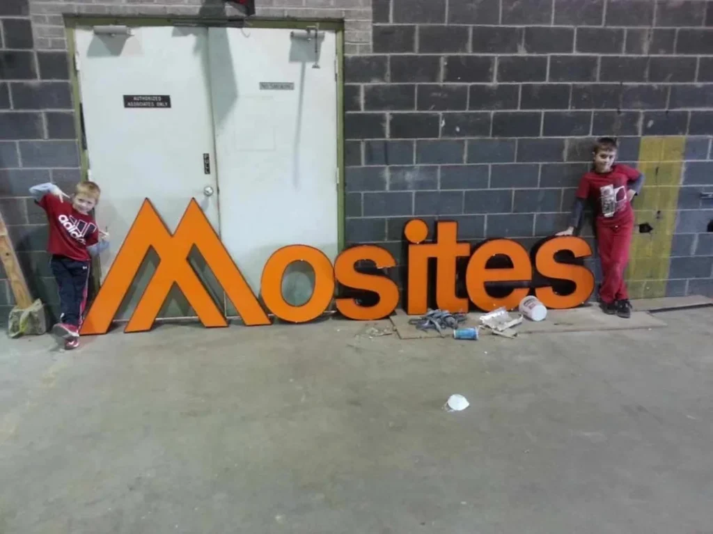 a group of kids standing next to a large orange sign